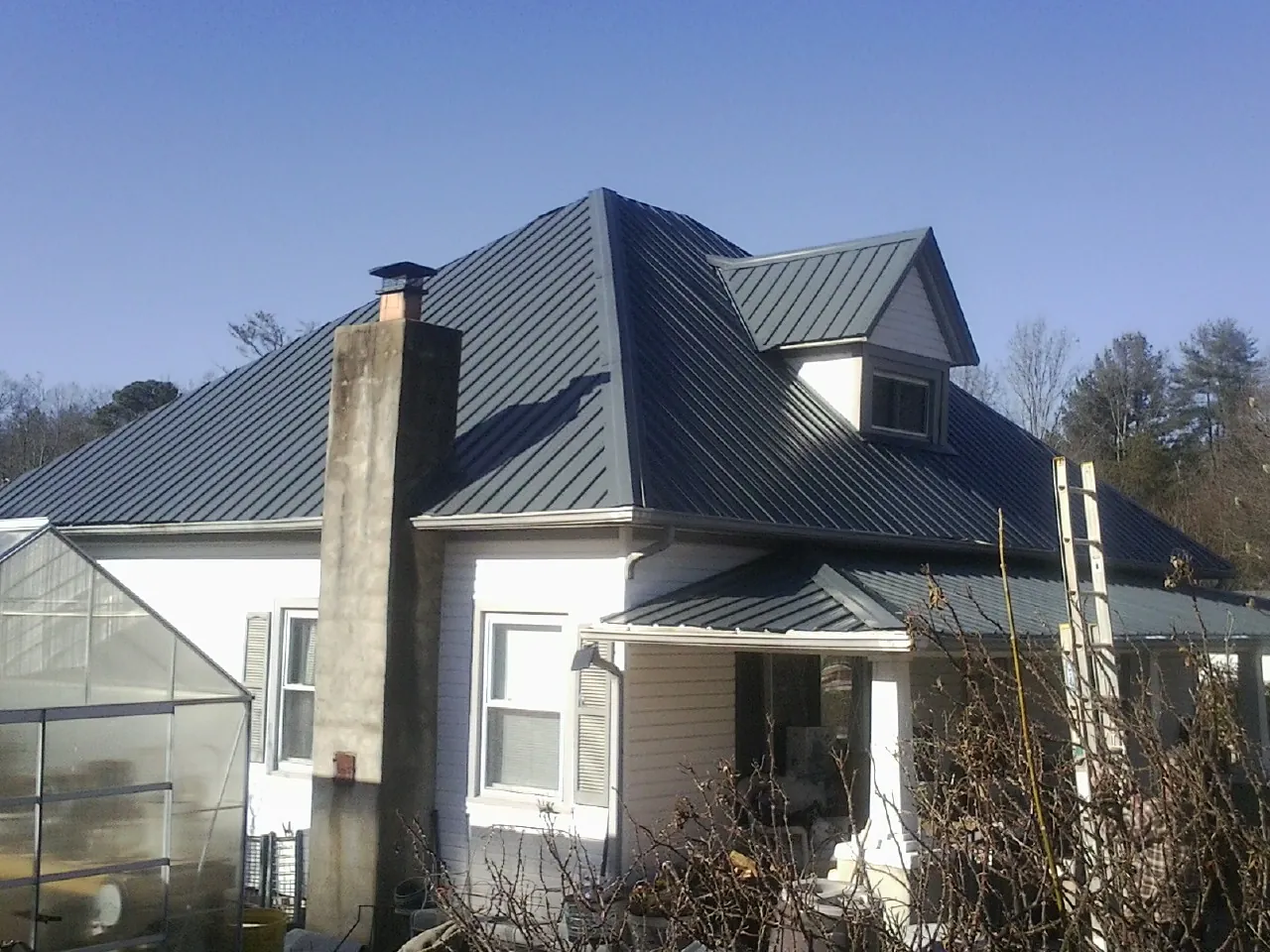 Dark blue standing seam metal roof on a white farmhouse with dormer — Slate & Tile Roof Repair by Roofing Brothers in Mehama