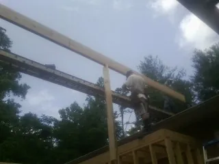 Carpenter setting a ridge beam over a new addition frame — Ice Dam Removal by Roofing Brothers in Mehama
