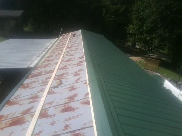 Old rusted panels beside newly installed green metal roofing — Wind Damage Roof Repair by Roofing Brothers in Mehama