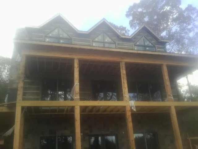 Dormers and porch framing on a large log home under construction — Roof Coating work by our crew in Mehama