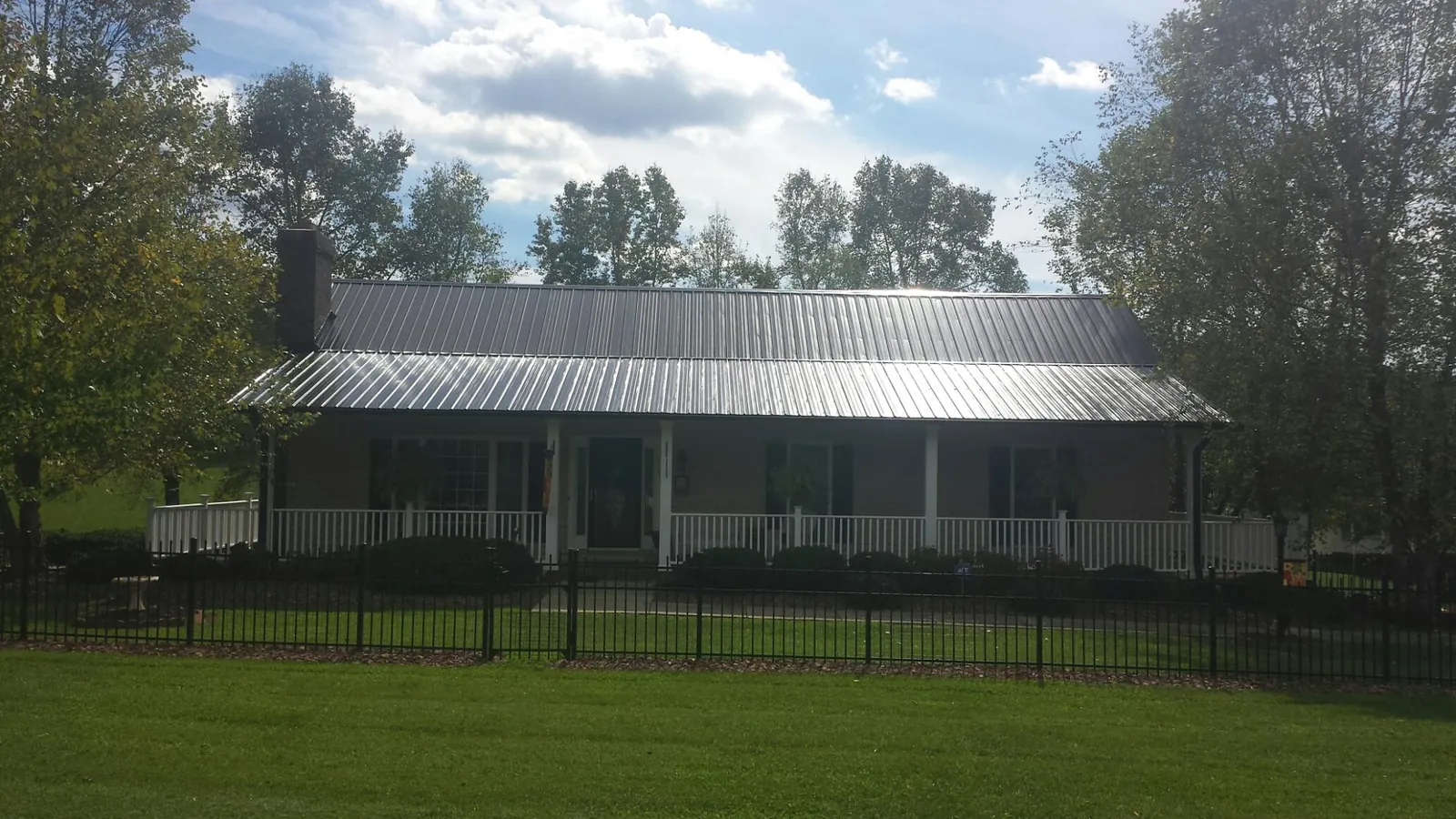 Gray metal roof on a brick ranch with a full width front porch — Gutter Guard Installation work by our crew in Mehama