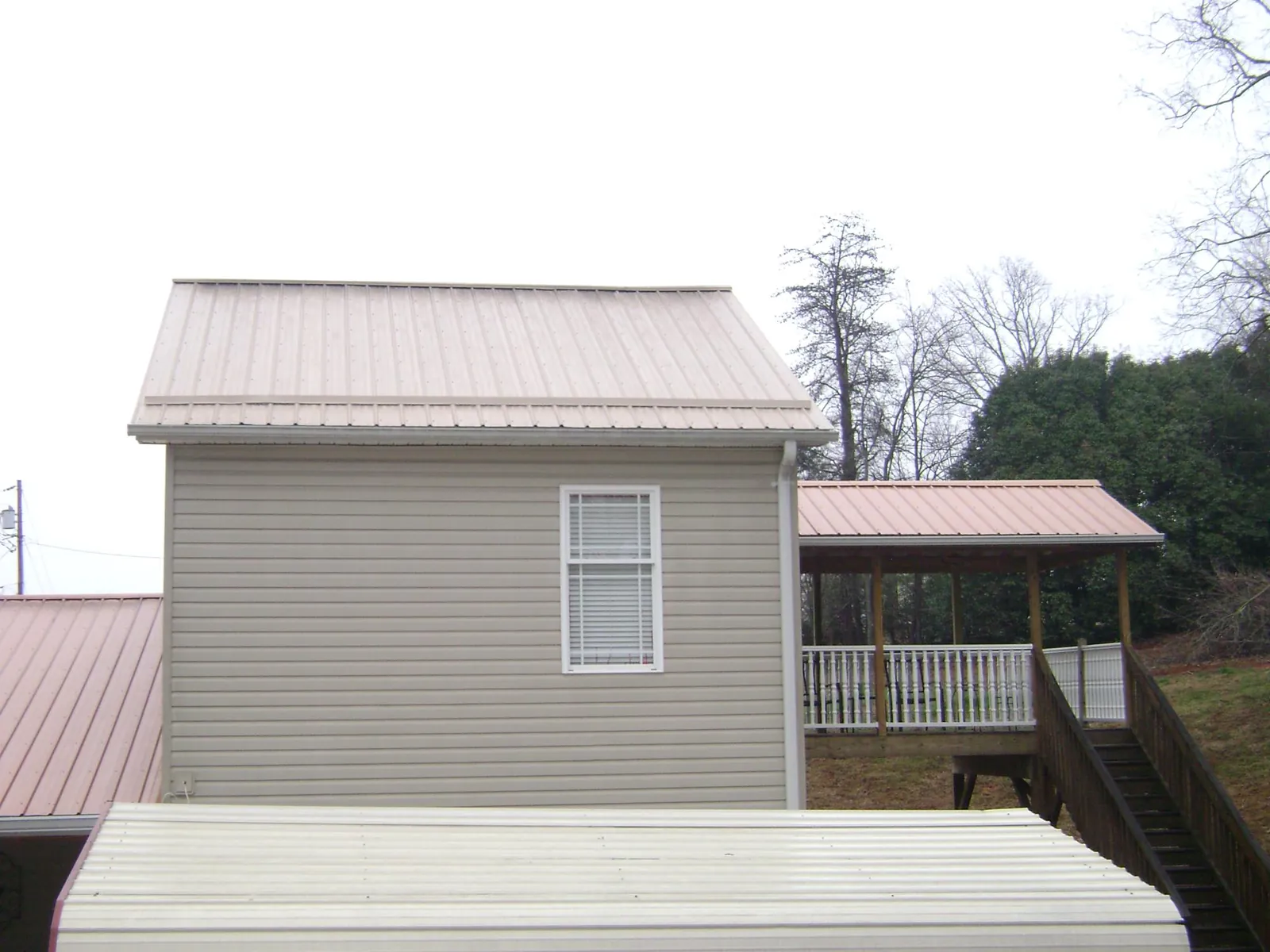 Tan metal roofs on a two story addition and attached porch, from a Roof Replacement job in Mehama