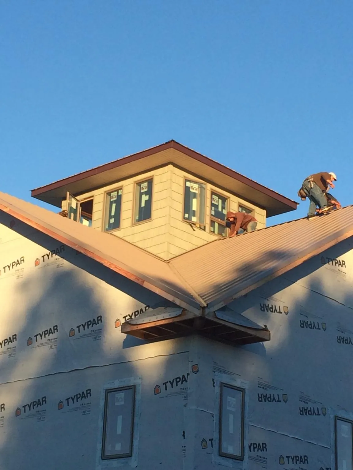 Roofers working around a rooftop cupola on a new metal roof at sunset — Roof Waterproofing in Mehama by Roofing Brothers